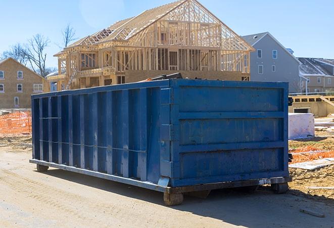 stacks of wallboard and wood planks tossed into a dumpster